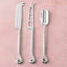 Three elegant cheese tools with spiral handles on a soft pink background. 
